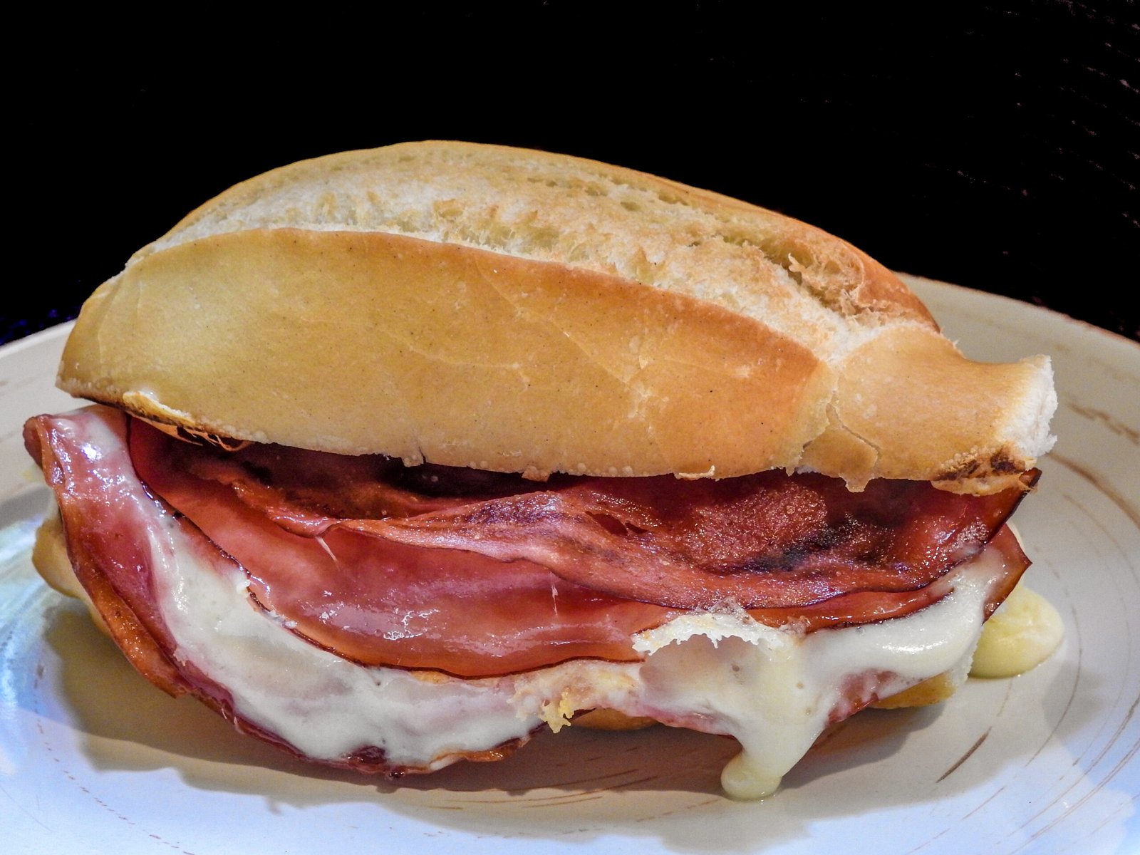 primer plano de un sandwich de tocino en un plato contra un fondo negro